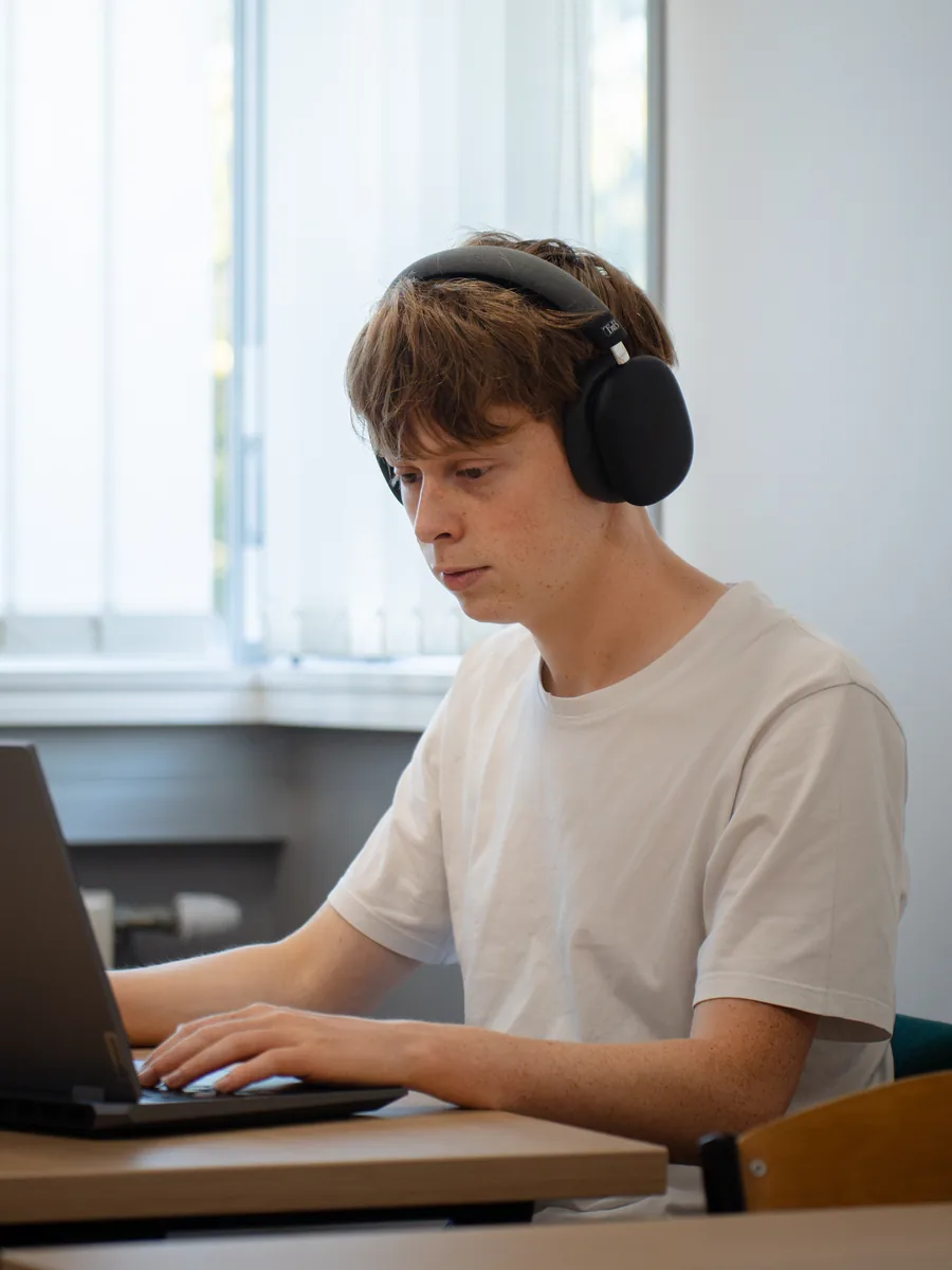 Portrait de Louis Girault, casque sur les oreilles, travaillant sur son ordinateur